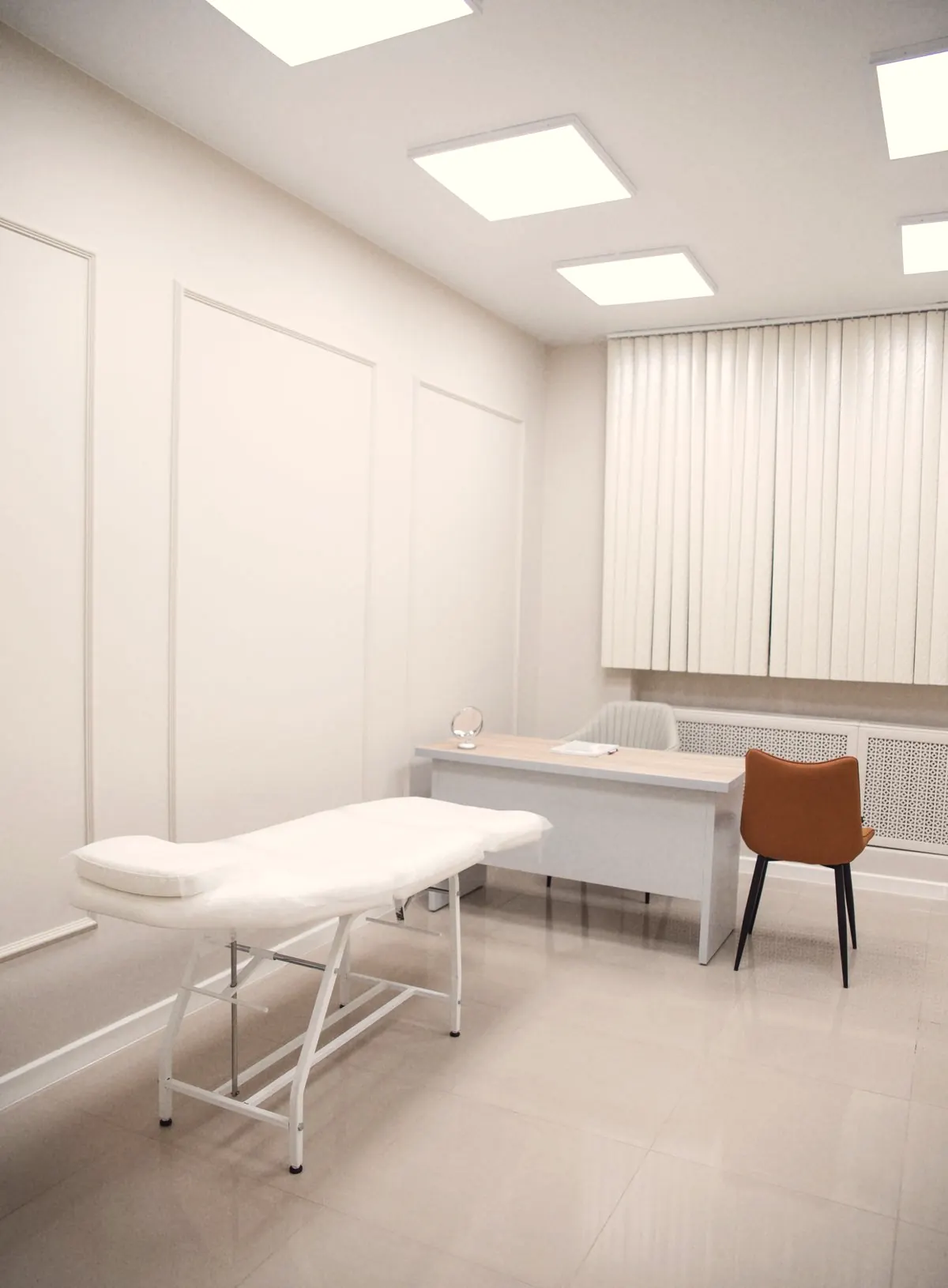 A calm, private consultation room with an examination bed, desk and chair