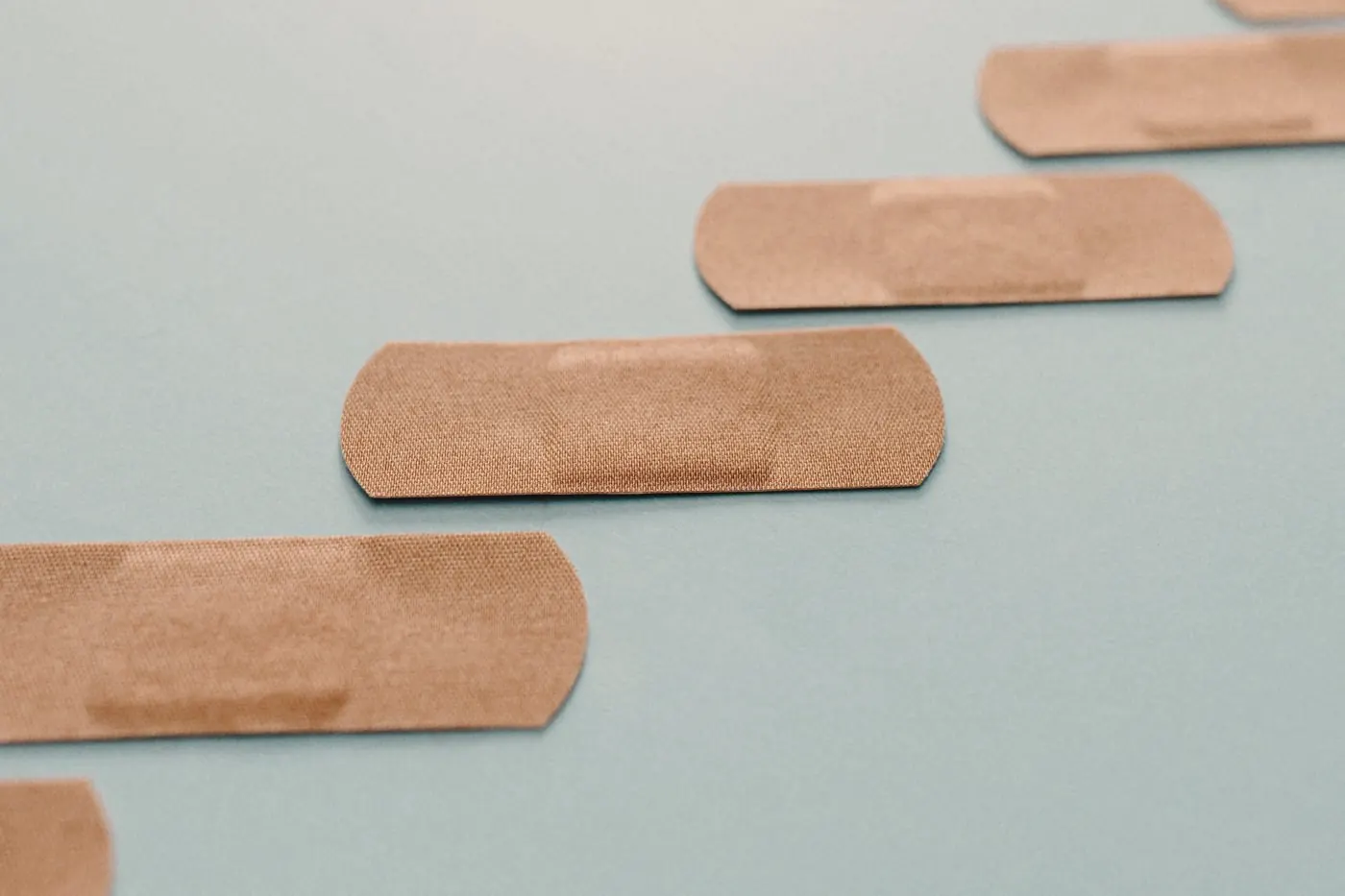 A row of skin-tone adhesive plasters laid out on a soft blue background
