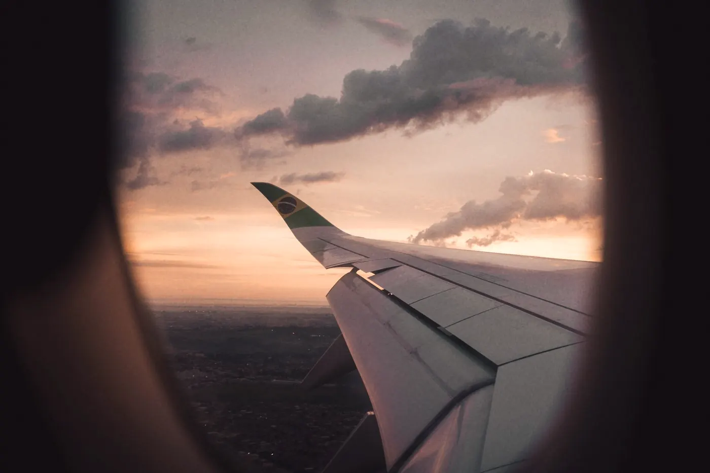 View of an aeroplane wing at sunset through a cabin window on a long-haul flight