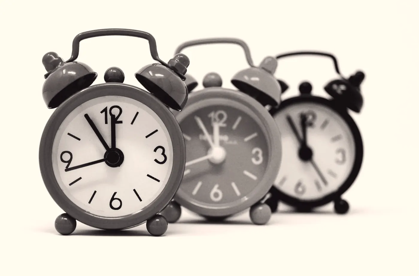 Three alarm clocks in black and white, a reminder to book follow-up HIV tests on time