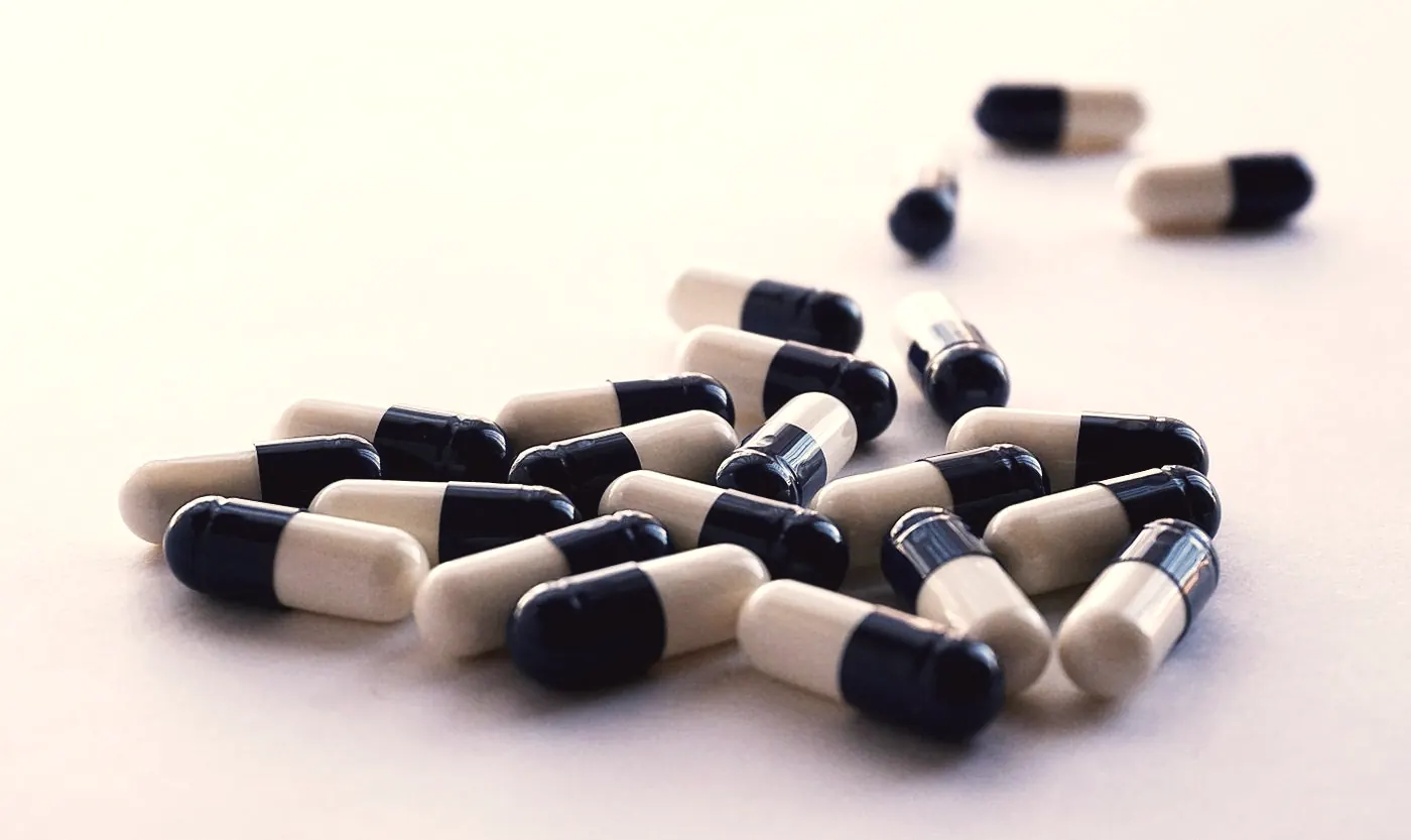 Two-tone antibiotic capsules scattered on a white surface, as used to treat bacterial STIs