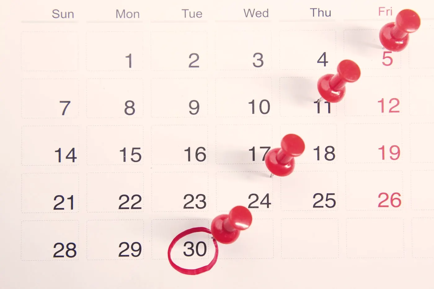 A calendar with red push pins marking dates, like planning follow-up HIV tests