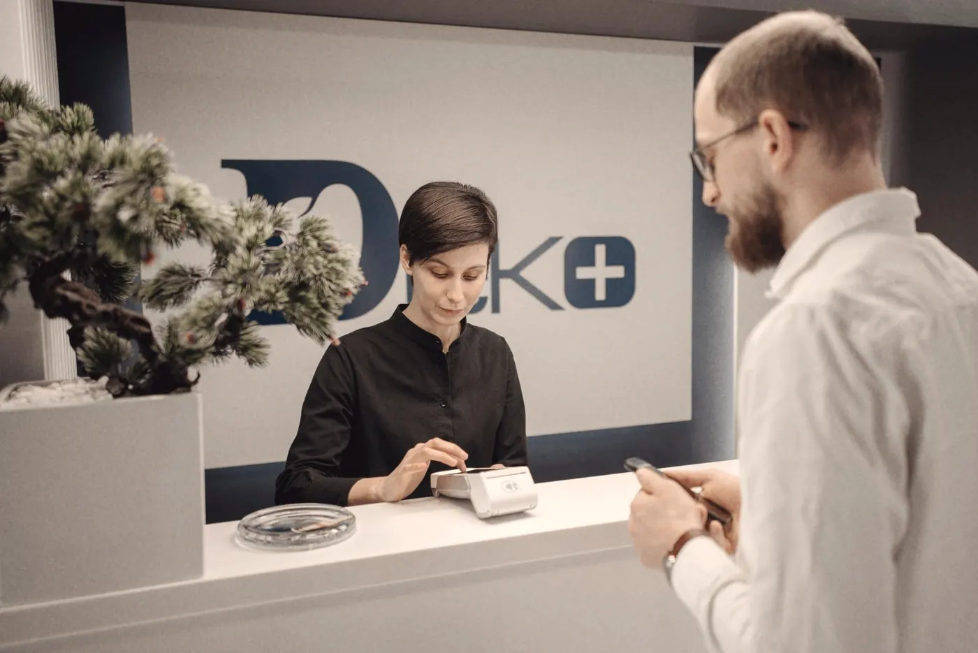 A patient paying by card at a clinic reception desk