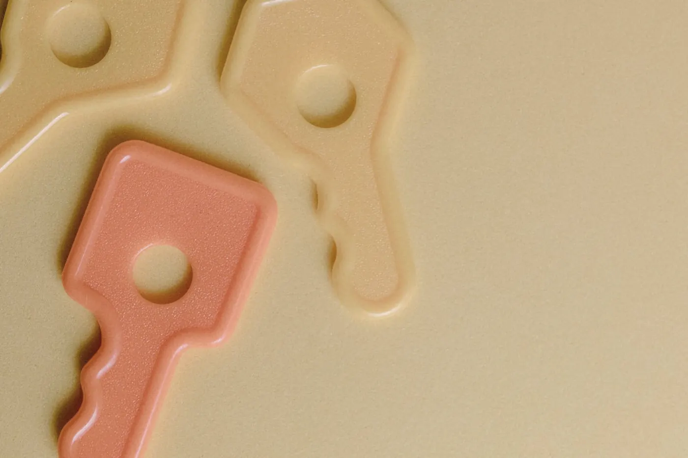 Colourful plastic keys of different shapes lying on a smooth yellow surface