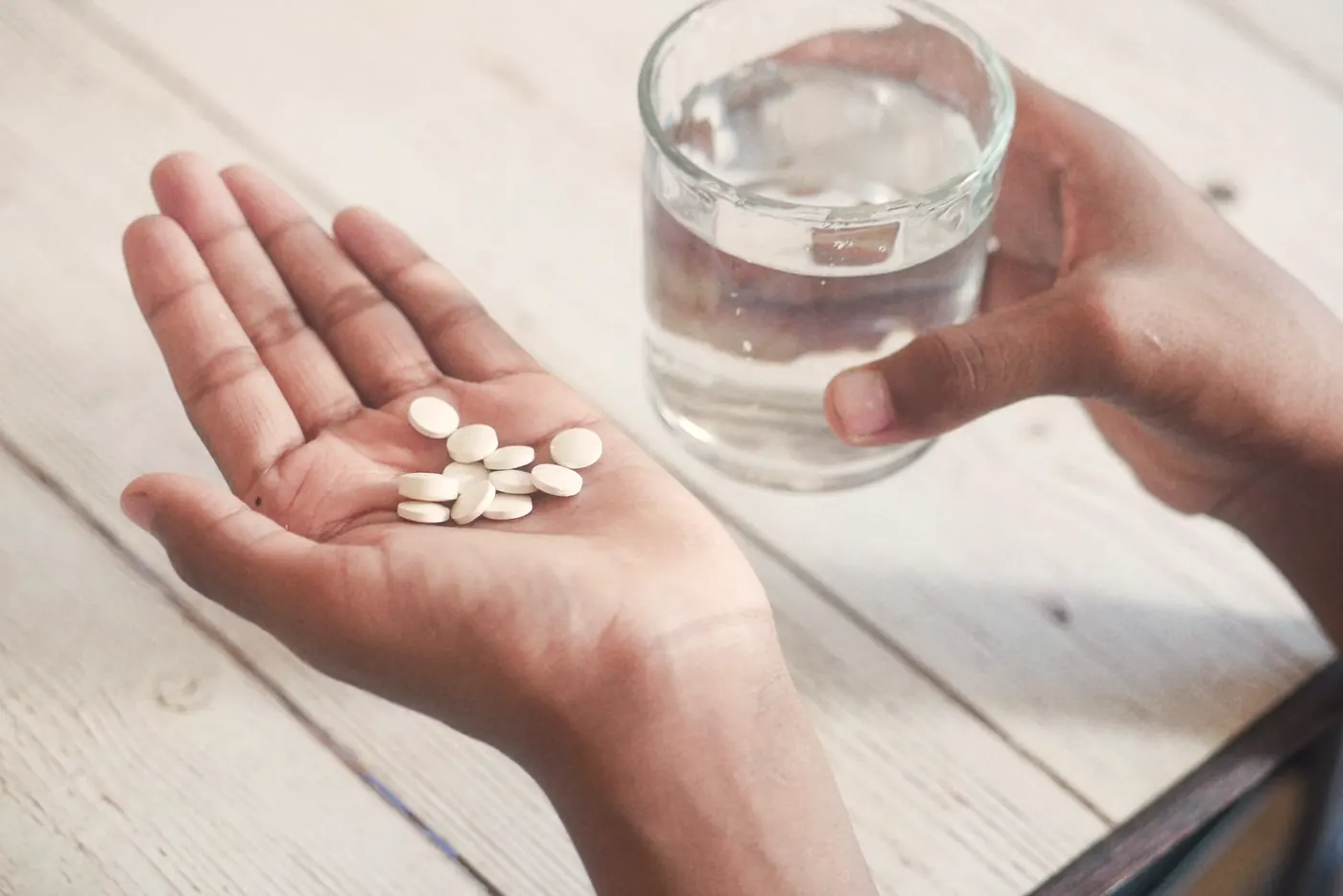 Hands holding a pill and a glass of water, as with emergency contraception