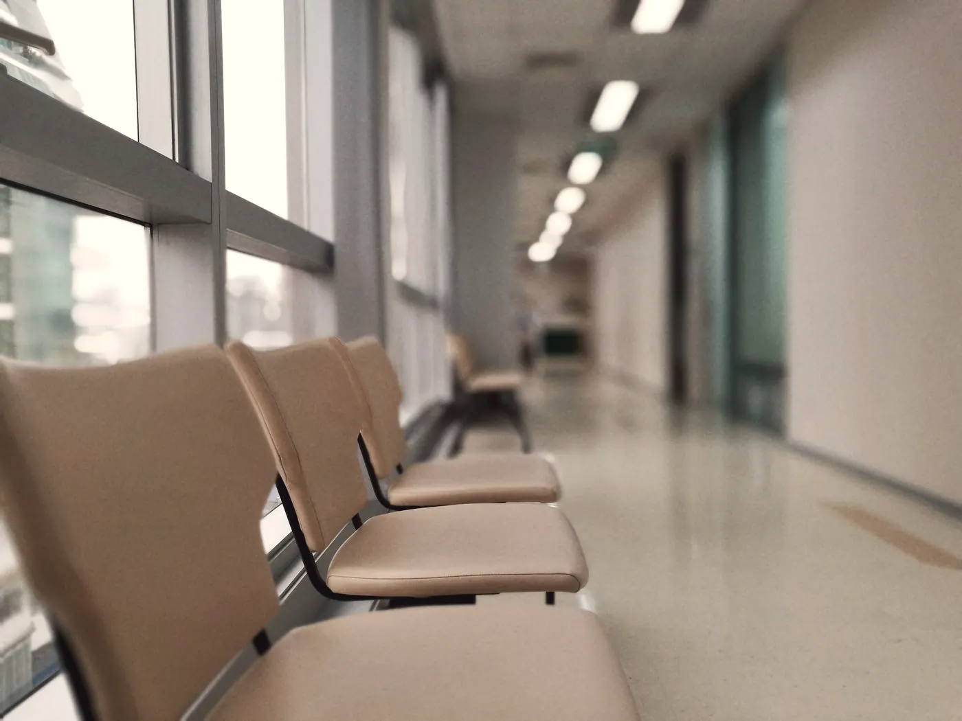 A row of empty waiting chairs in a hospital corridor with soft light