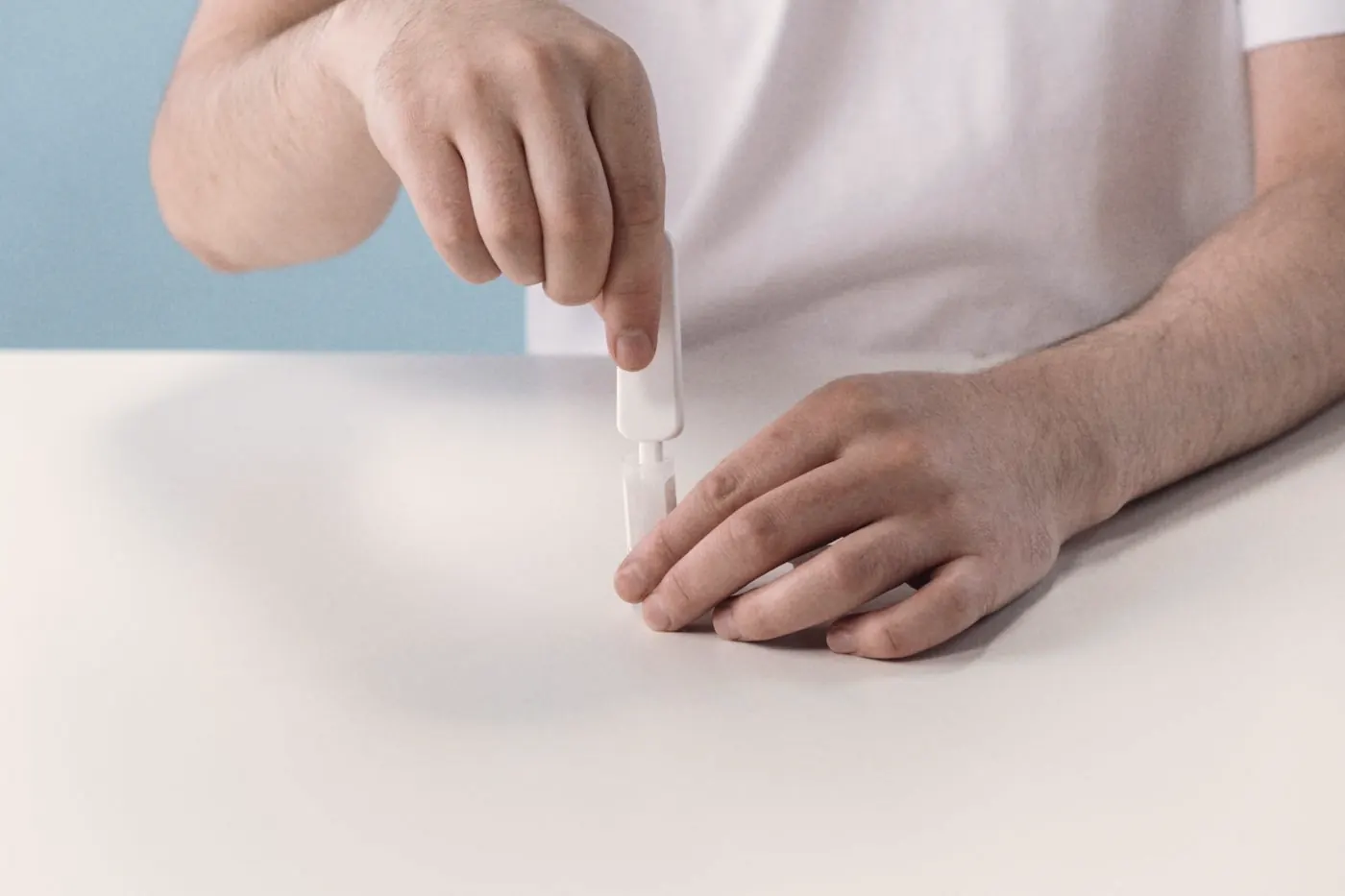 Hands preparing an oral HIV self-test kit on a clean white table at home