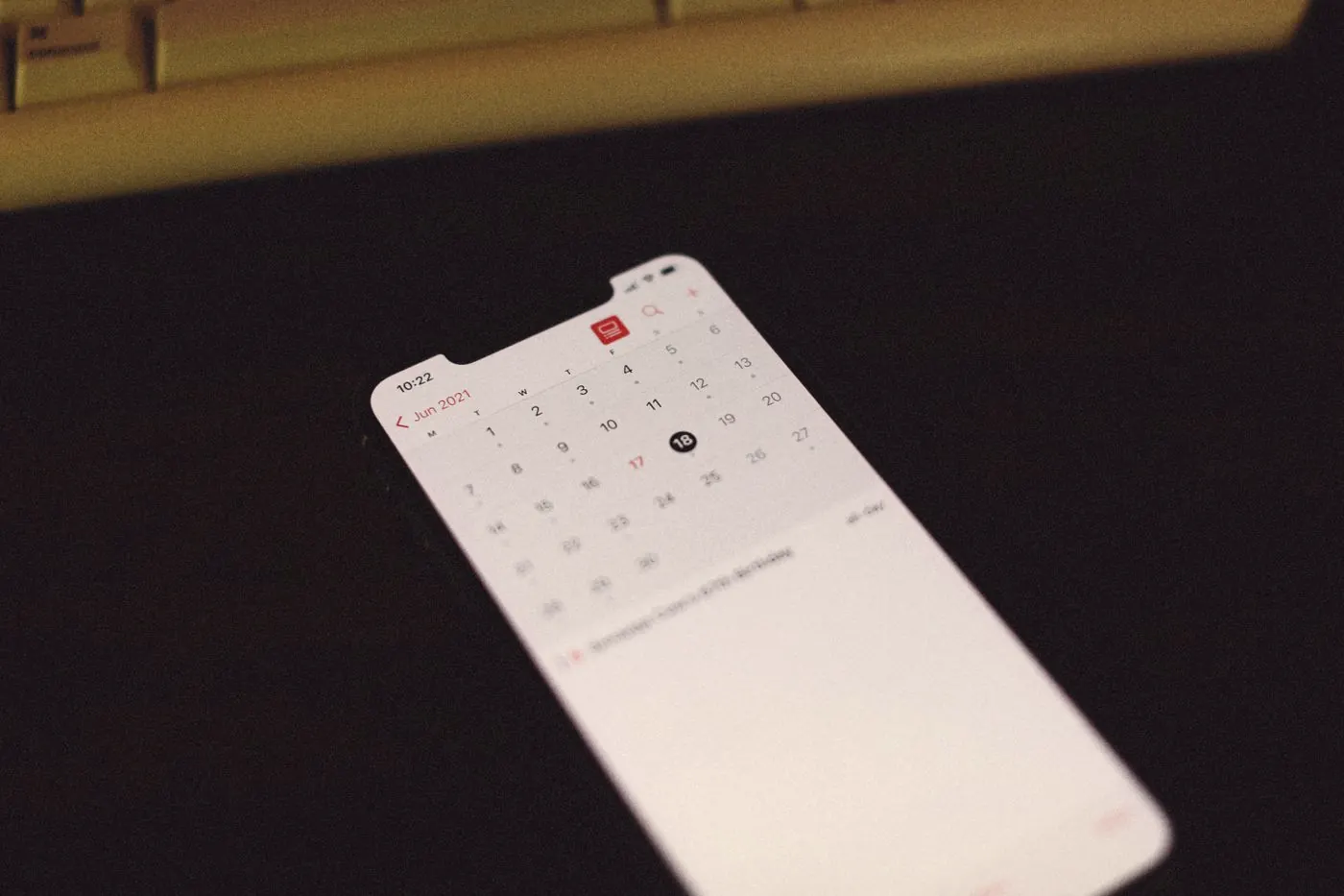 A smartphone showing a calendar app on a dark table, with follow-up test dates saved