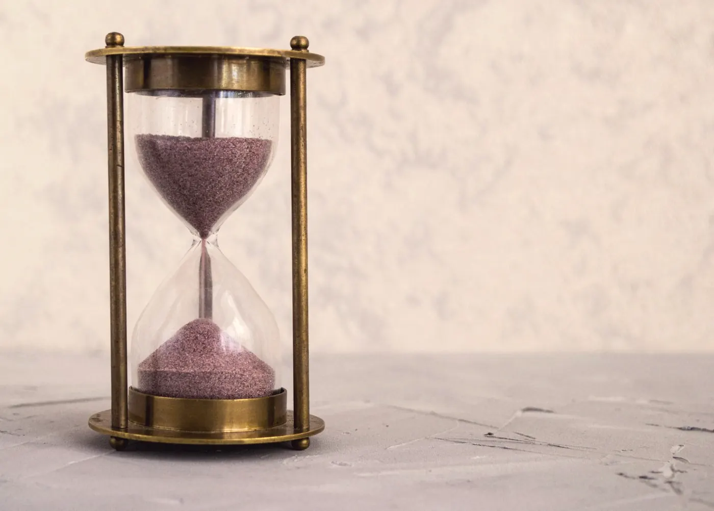 A brass hourglass with pink sand, a reminder that STI tests need the right timing