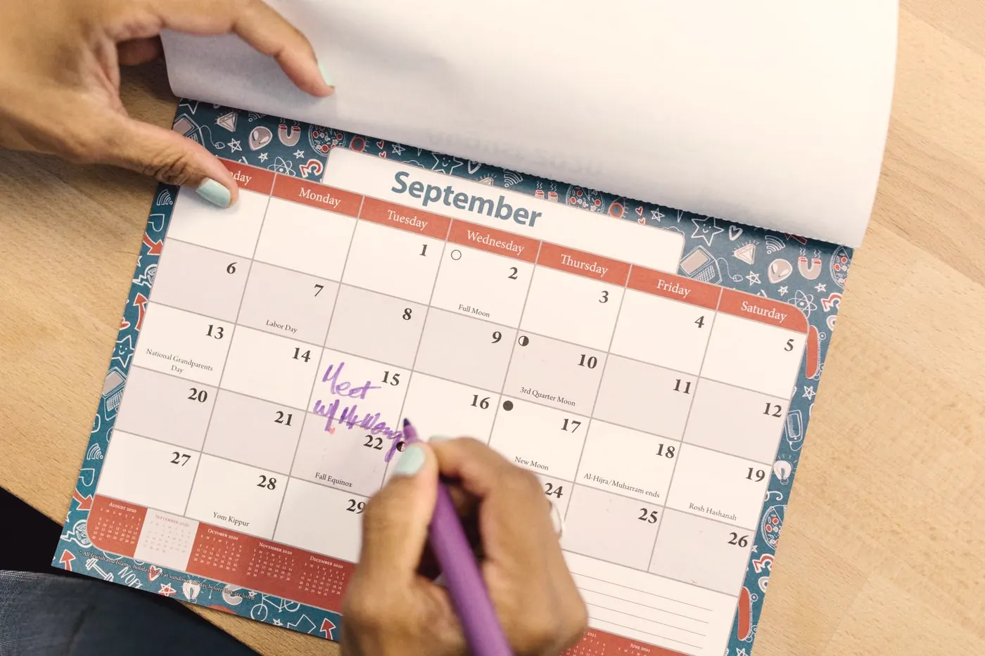A hand marking dates on a September calendar with a purple pen to track daily doses