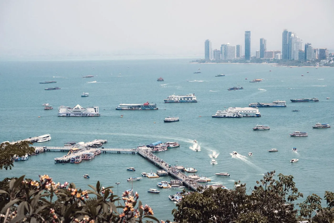 Boats moored in a harbour in Pattaya City with the coastline in the background