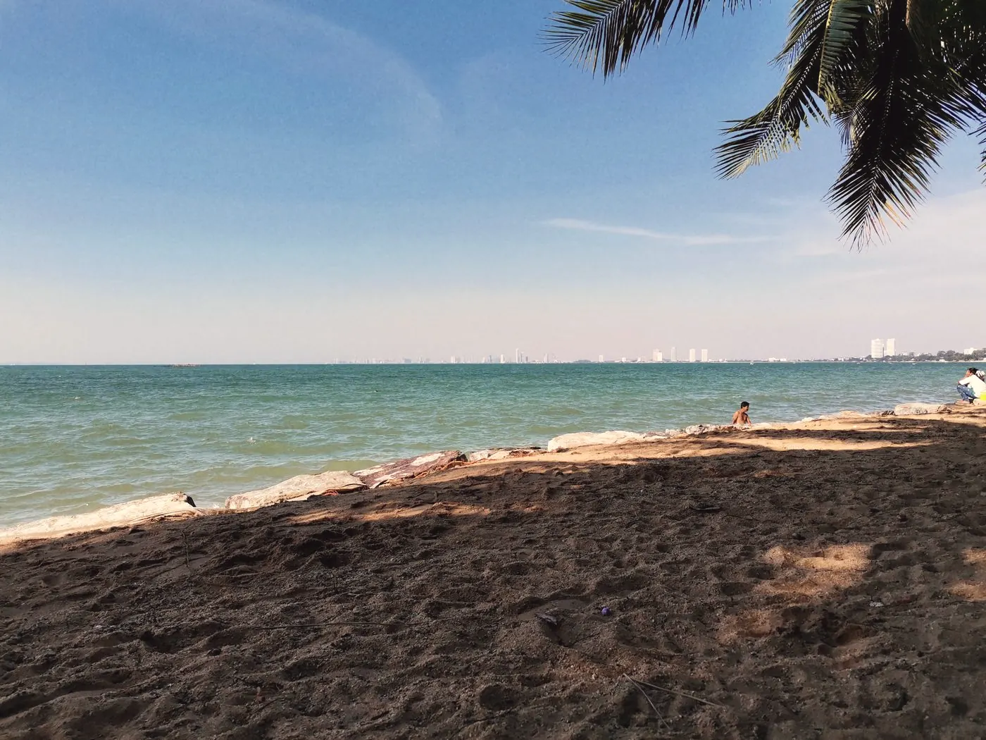 A quiet sandy beach in Pattaya with turquoise water under a clear blue sky