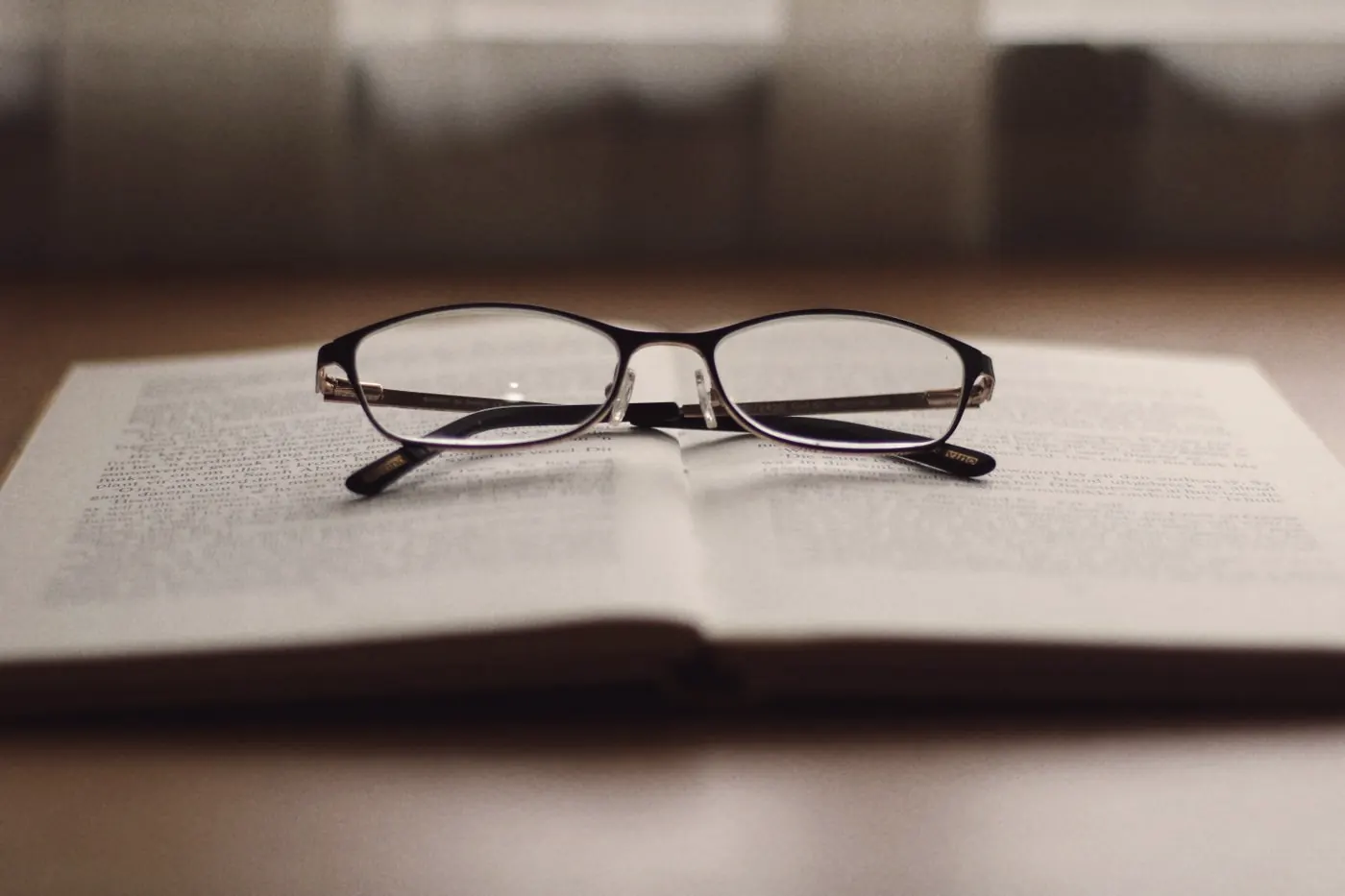 Reading glasses resting on an open book, like comparing UK, US and Thai testing guidelines