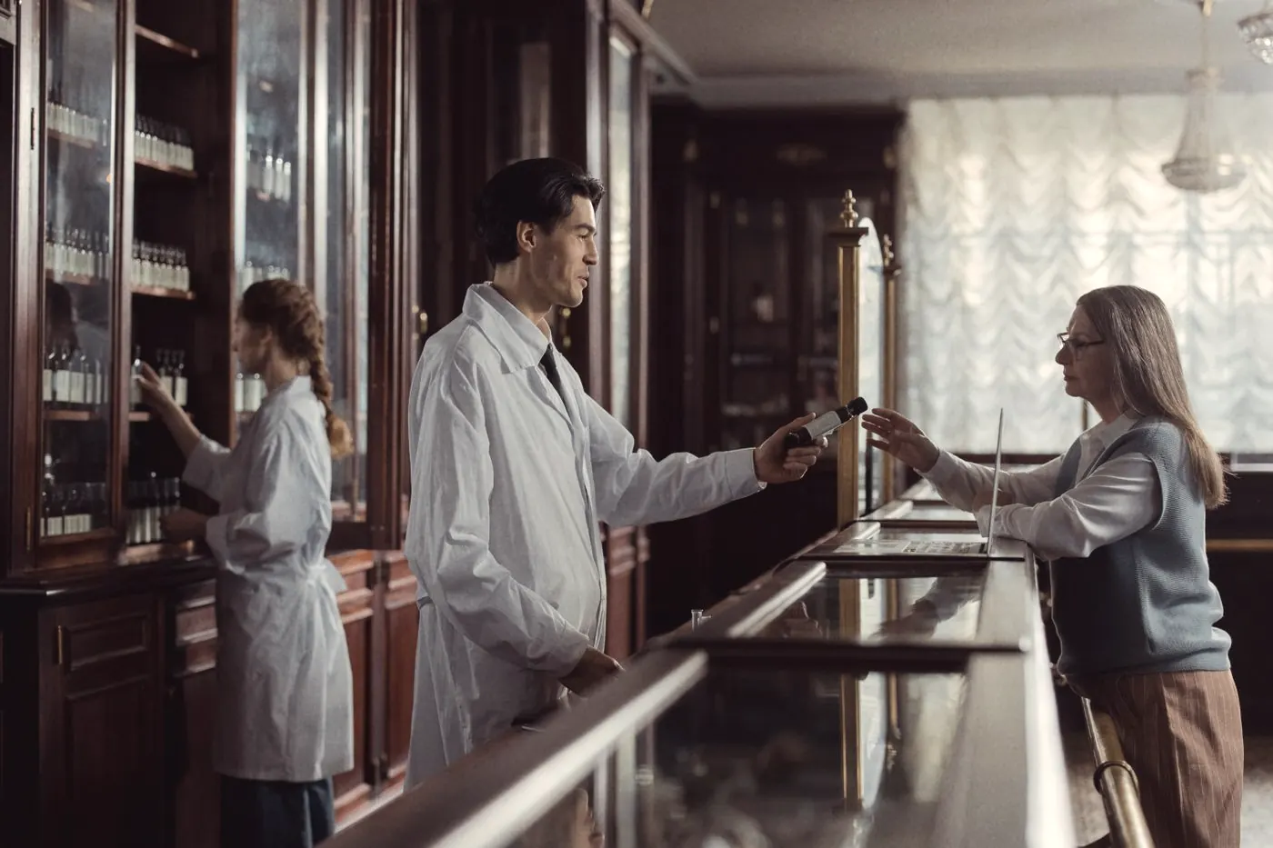 A pharmacist handing medicine to a customer at the counter