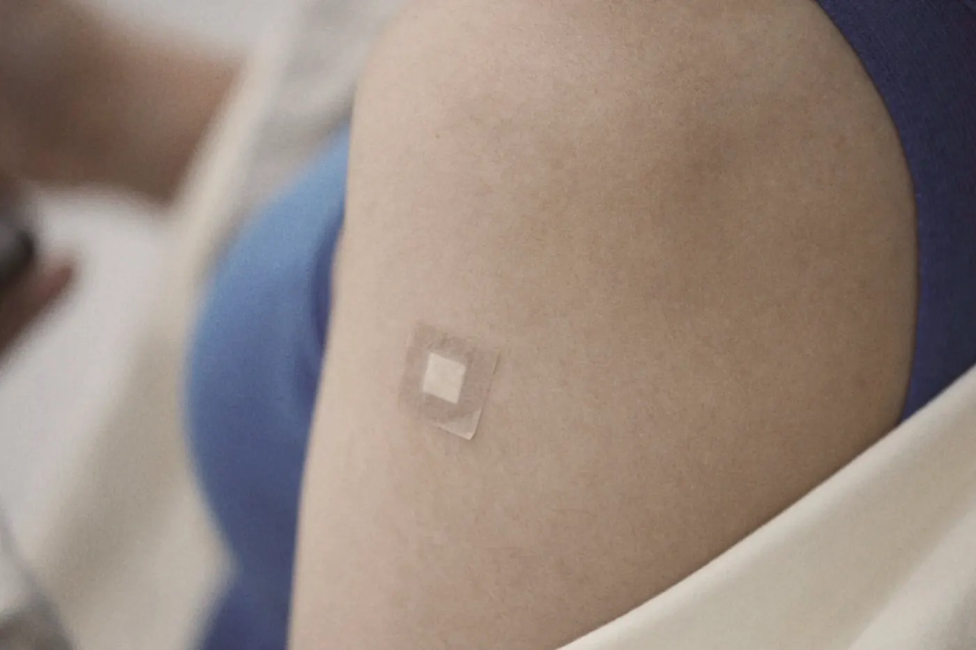 A small round plaster on an upper arm after a vaccination