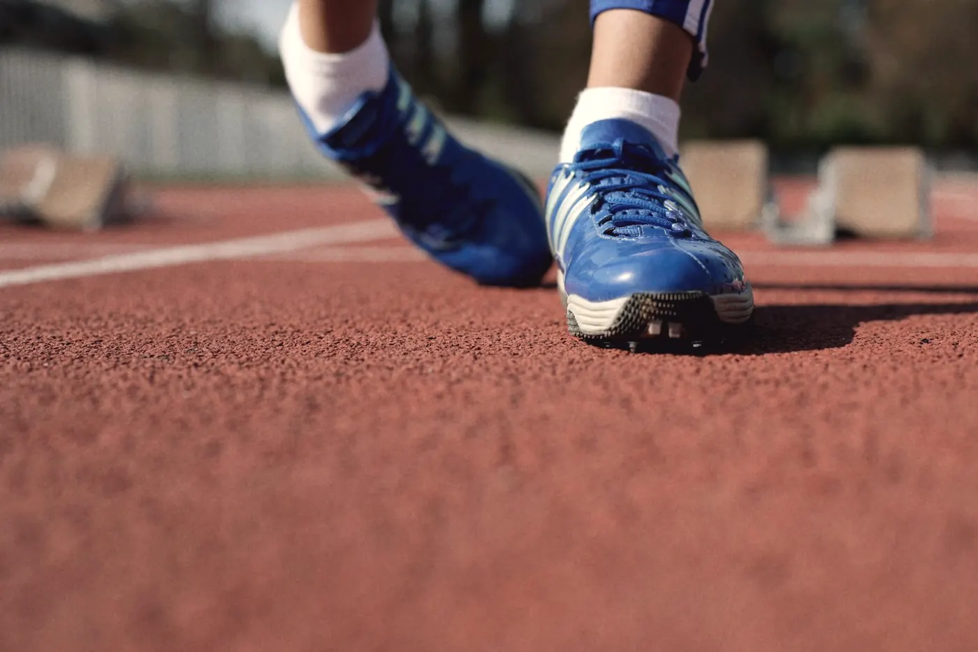 Close-up of blue running shoes on an outdoor track, weight-bearing exercise for bones
