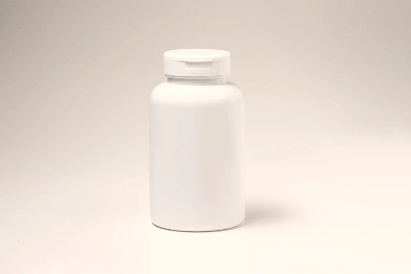 A plain white prescription medicine bottle standing on a light background