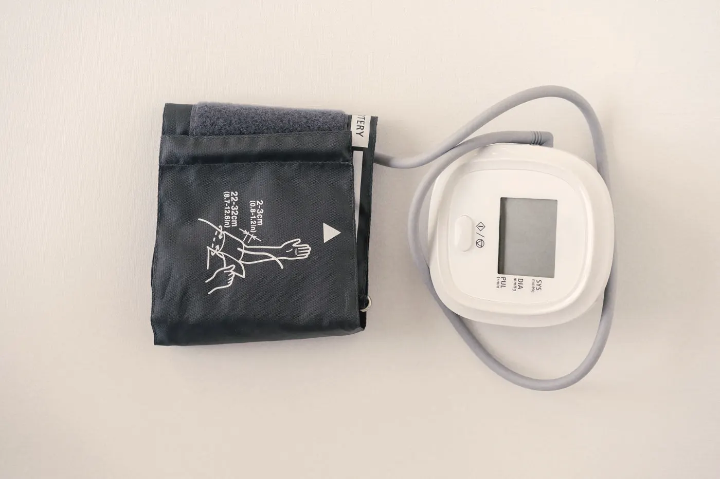 A digital health monitor and cuff on a white surface, ready for a routine check