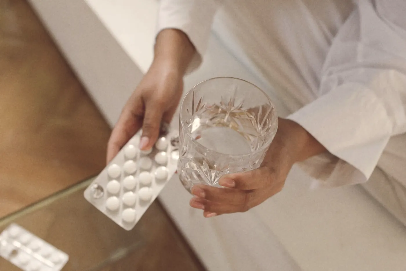 Hands holding a tablet and a glass of water to take PrEP