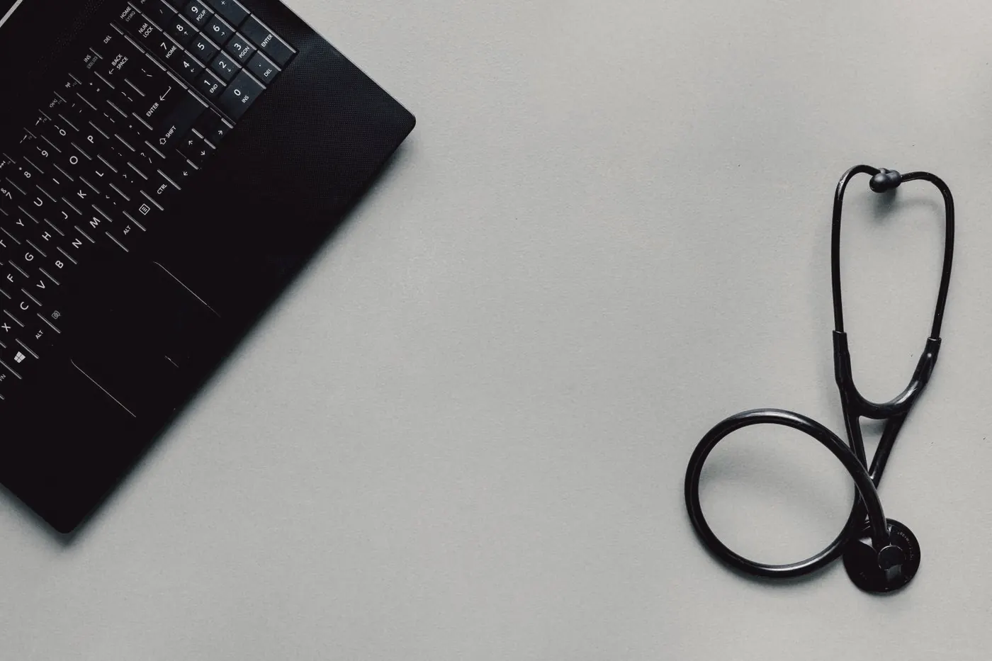 A laptop and a stethoscope on a desk, representing an online doctor consultation