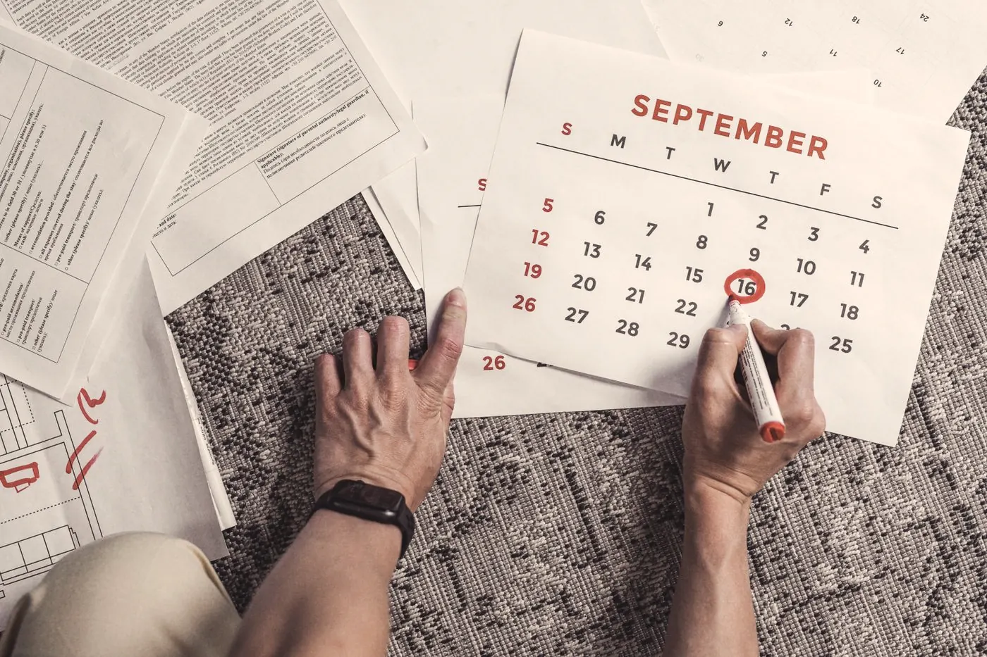 Hands circling dates on a September calendar while planning a trip