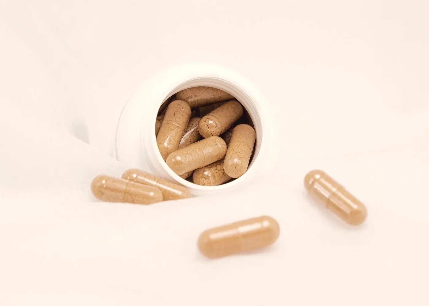 Supplement capsules spilling from a white bottle, a reminder to space minerals away from PEP