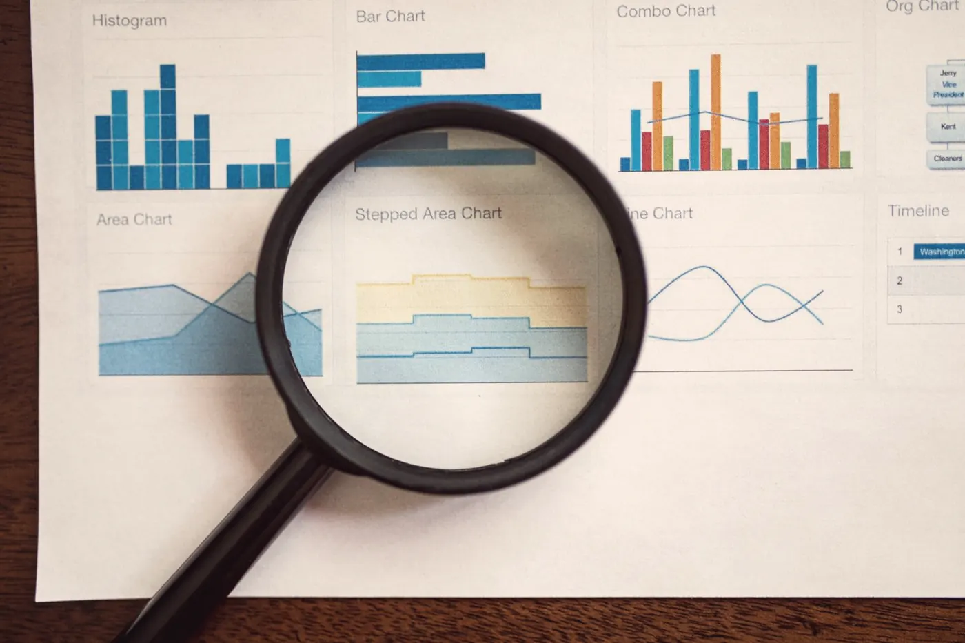 A magnifying glass resting on printed charts and graphs, like checking HIV data