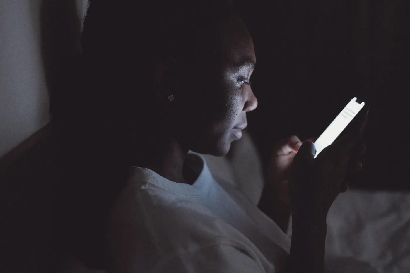 A person in a dark bedroom searching on their phone after a condom broke